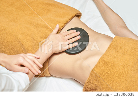 Asian Female Receiving Hot Stone Therapy For Relaxation In Spa Setting Focused On Wellness Asian Female Receiving Hot Stone Therapy For Relaxation In Spa Setting Focused On Wellness 138300039