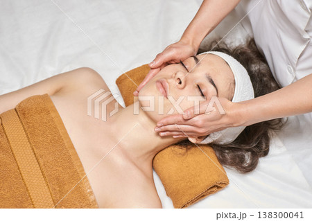 Young Caucasian Female Enjoying Relaxing Face Massage At Spa With Professional Therapist 138300041