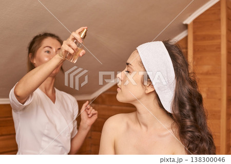 Young Caucasian Female Enjoying Relaxing Facial Treatment In Spa With Spritzing Mist In Wooden Young Caucasian Female Enjoying Relaxing Facial Treatment In Spa With Spritzing Mist In Wooden 138300046