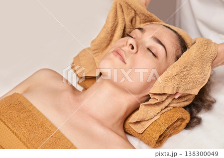 Young Caucasian Female Relaxing During Spa Treatment With Towels At Wellness Center Young Caucasian Female Relaxing During Spa Treatment With Towels At Wellness Center 138300049