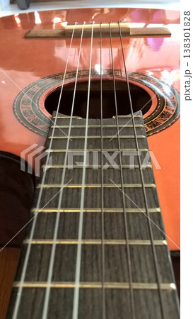 Acoustic guitar guitar string fret sound hole wooden instrument music closeup detail artistic reflection Acoustic guitar fretboard closeup with metal string leading toward ornate sound hole Acoustic guitar guitar string fret sound hole wooden instrument music closeup detail artistic reflection Acoustic guitar fretboard closeup with metal string leading toward ornate sound hole 138301828