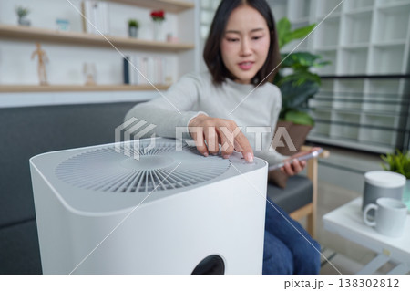Woman adjusting air purifier settings in modern living room 138302812