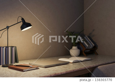 Closed laptop and open book and pencil under lamp light on marble counter table in dim room at night 138303770