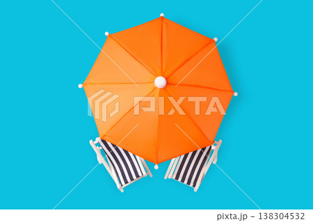 Orange umbrella and striped chairs sit on blue space 138304532