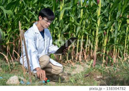 Asian agricultural researcher man holding clipboard checking water supply while sitting in crop farm Asian agricultural researcher man holding clipboard checking water supply while sitting in crop farm 138304782