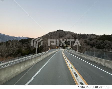 夕暮れの山間部を走る道路とカーブする進行方向 138305537