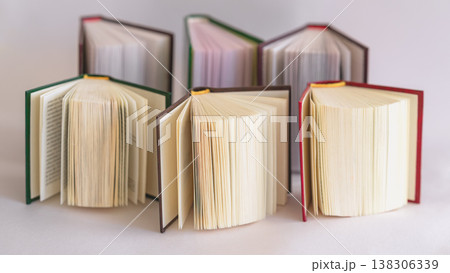 Open books with open pages arranged in semicircle composition isolated on light background showing paper texture, binding, reading. Concept of education, knowledge, book collection, reading culture Open books with open pages arranged in semicircle composition isolated on light background showing paper texture, binding, reading. Concept of education, knowledge, book collection, reading culture 138306339