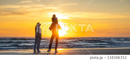 Family enjoying togetherness watching colorful ocean sunset Family enjoying togetherness watching colorful ocean sunset 138306352