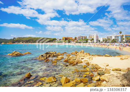 Selective focus. Rocky Mediterranean beach with turquoise water and busy seaside resort Selective focus. Rocky Mediterranean beach with turquoise water and busy seaside resort 138306357