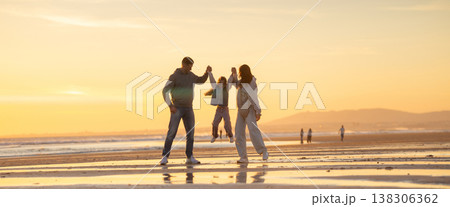 Child jumping between parents on beach at sunset Child jumping between parents on beach at sunset 138306362