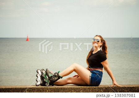 Happy young woman wearing roller skates Happy young woman wearing roller skates 138307081