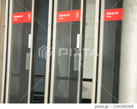 Glass doors with no entry sign at building entrance. Red warning label on transparent door frame indicating restricted area. Prohibition safety signal for public access control concept. 138308304