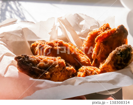Crispy fried chicken wings in paper basket. Appetizing fast food snack served in container. Hot greasy roasted poultry pieces for lunch or dinner menu. Fresh crunchy snack concept. Crispy fried chicken wings in paper basket. Appetizing fast food snack served in container. Hot greasy roasted poultry pieces for lunch or dinner menu. Fresh crunchy snack concept. 138308314