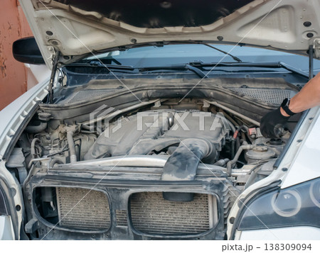 Mechanic inspecting car engine with open hood. Professional auto technician checking vehicle component under bonnet. Automotive maintenance service, repair work in garage, motor diagnostic. 138309094