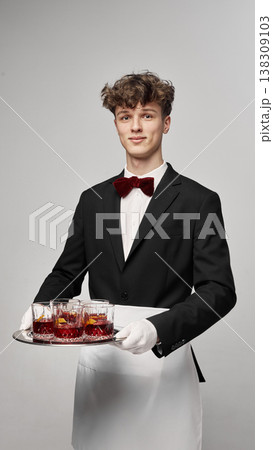 Waiter serving tray with multiple red cocktails in glasses in clean studio setup. 138309103