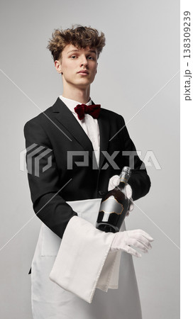 Waiter presenting champagne bottle in stylish studio portrait with confident posture. Waiter presenting champagne bottle in stylish studio portrait with confident posture. 138309239