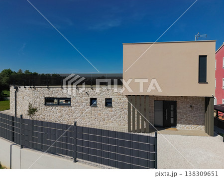 Modular modern smart automated house with stone facade and unfinished areas seen from aerial drone view 138309651