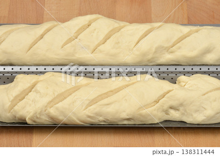 Raw baguette dough on a baking tray on a wooden surface 138311444