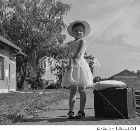 Adorable little girl on a railway station, waiting for the train with vintage suitcase. Traveling, holiday and chilhood concept. Travel insurance concept. Travel, tourism, summer vacation and family Adorable little girl on a railway station, waiting for the train with vintage suitcase. Traveling, holiday and chilhood concept. Travel insurance concept. Travel, tourism, summer vacation and family 138311751