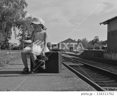 Young girl with suitcase and teddy bear waiting on a train platform Young girl with suitcase and teddy bear waiting on a train platform 138311762