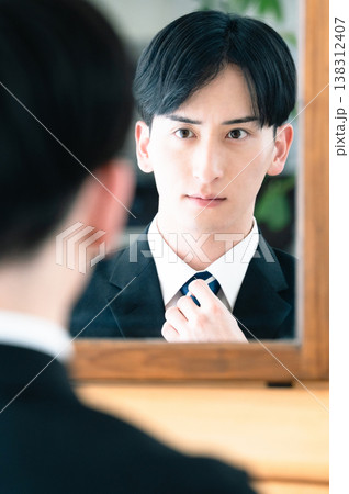 鏡の前でネクタイを締めるスーツ姿の男性 138312407