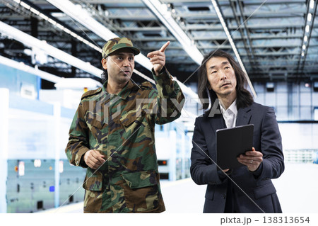 Military man and senior manager manufacturing semiconductors to win chip war, using tablet. Industrial plant director and soldier using device to inspect silicon wafers used in army defense equipment Military man and senior manager manufacturing semiconductors to win chip war, using tablet. Industrial plant director and soldier using device to inspect silicon wafers used in army defense equipment 138313654