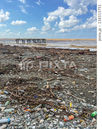 A littered pebble beach with rough waves and accumulations of debris and plastic. A littered pebble beach with rough waves and accumulations of debris and plastic. 138313751