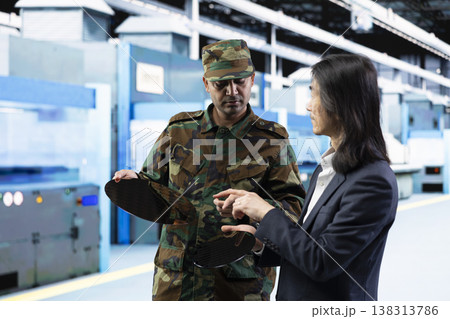 Army man talks with senior manager about using silicon wafer supply chain for national security purposes. Military soldier and Asian director reviewing strategic microelectronics factory production Army man talks with senior manager about using silicon wafer supply chain for national security purposes. Military soldier and Asian director reviewing strategic microelectronics factory production 138313786