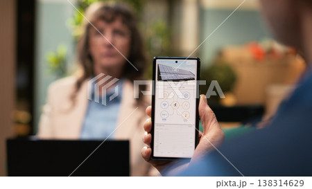 Aged man and woman reviewing green energy system through software on mobile phone. Sustainable, eco and clean power solutions like photovoltaic panels and off-grid solar energy at home. Aged man and woman reviewing green energy system through software on mobile phone. Sustainable, eco and clean power solutions like photovoltaic panels and off-grid solar energy at home. 138314629
