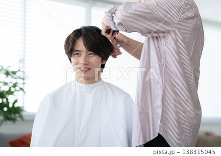 ヘアサロンでヘアカットをしてもらう若い男性 ヘアサロンでヘアカットをしてもらう若い男性 138315045