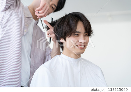 ヘアサロンでヘアカットをしてもらう若い男性 ヘアサロンでヘアカットをしてもらう若い男性 138315049