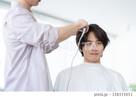ヘアサロンでヘアカットをしてもらう若い男性 138315051