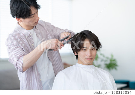 ヘアサロンでヘアカットをしてもらう若い男性 138315054