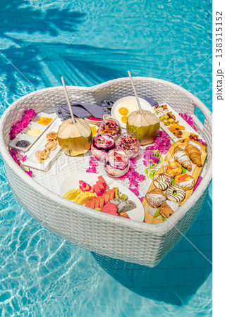 Luxury resort swimming pool close-up with floating breakfast heart shape tray, romantic couple honeymoon anniversary tropical vacation background Luxury resort swimming pool close-up with floating breakfast heart shape tray, romantic couple honeymoon anniversary tropical vacation background 138315152