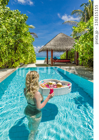 Luxury resort swimming pool with floating breakfast tray in heart shape, blonde woman relaxing, romantic honeymoon vacation tropical beach background Luxury resort swimming pool with floating breakfast tray in heart shape, blonde woman relaxing, romantic honeymoon vacation tropical beach background 138315155