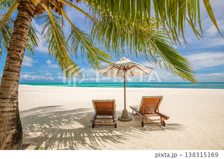 Sunny tropical beach with couple chairs, umbrella, palm trees, and ocean view, relaxing vacation tropical island travel landscape 138315169