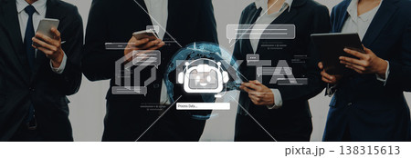 Group of business professionals using smartphones and tablets while standing together with digital chatbot graphic overlay and communication icons in a modern office setting Trope 138315613