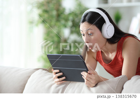 Surprised asian woman checking media content on tablet 138315670