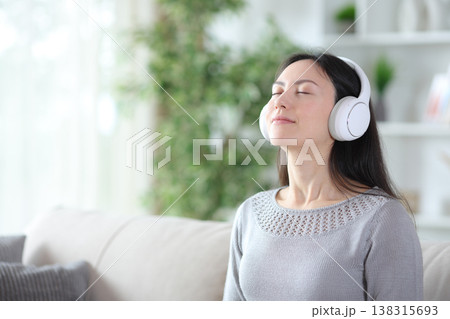 Asian woman wearing headphone breathing listening audio guide Asian woman wearing headphone breathing listening audio guide 138315693