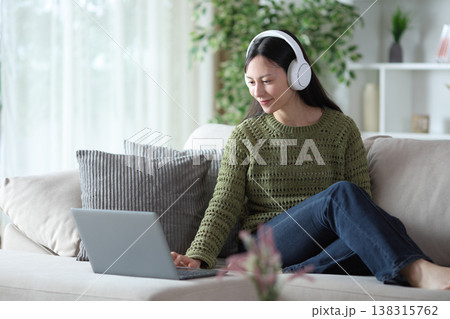 Asian woman wearing headphone checking computer Asian woman wearing headphone checking computer 138315762