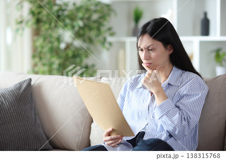 Suspicious asian woman reading form at home 138315768