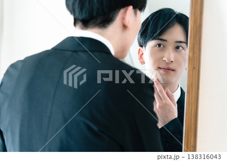鏡の前で身だしなみを整えるスーツ姿の男性 138316043