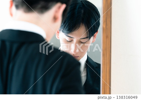 鏡の前で身だしなみを整えるスーツ姿の男性 138316049