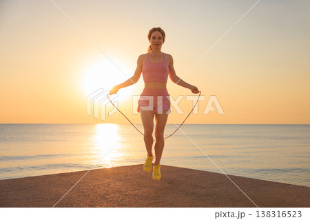 Fit woman jumping rope at the beach during summer vacation 138316523