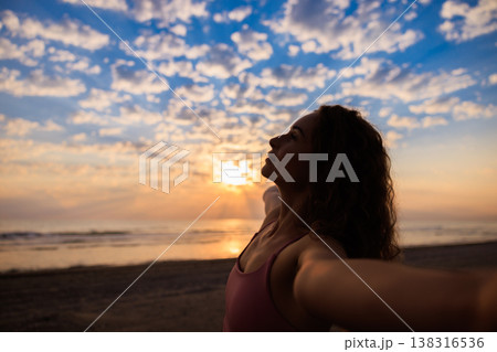 Happy woman enjoying sunrise at the beach during summer vacation Happy woman enjoying sunrise at the beach during summer vacation 138316536