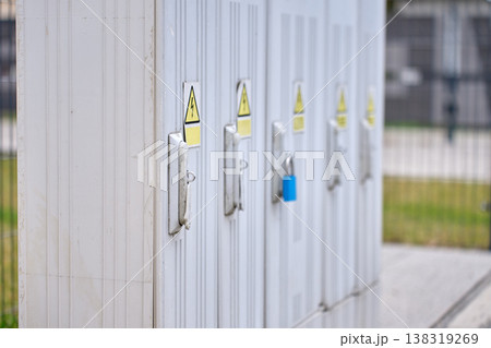 Row of outdoor electrical cabinets with warning signs and lock Row of outdoor electrical cabinets with warning signs and lock 138319269
