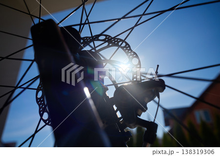 Close up of bicycle disc brake and spokes against sun 138319306