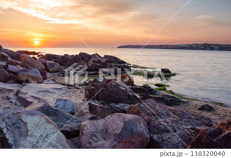 orange sunrise over the sea with rocky shore. beautiful summer scenery and vacation concept on the rocky beach. scenic destination of bulgaria seaside near old resort town 138320040