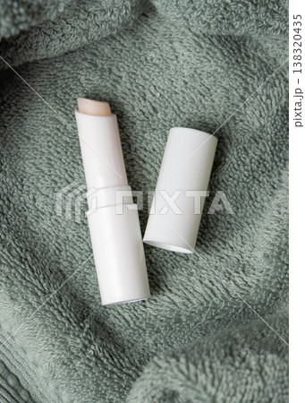 White opened lip balm stick mockup with a lid on sage green bath towel, unbranded packaging White opened lip balm stick mockup with a lid on sage green bath towel, unbranded packaging 138320435