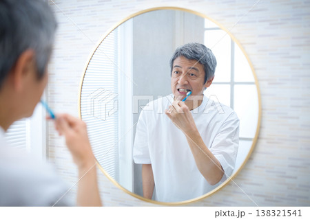 鏡を見ながら歯磨きをする60代の男性 138321541